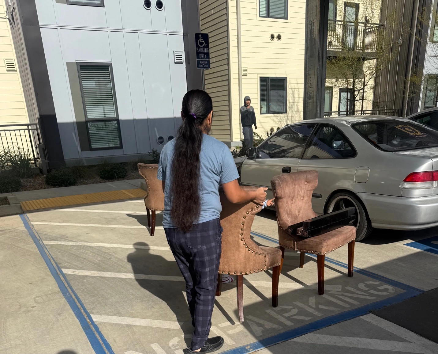 Person moving chairs in a parking lot.